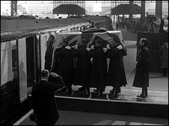 The bearer party places the coffin on the funeral train (PA)