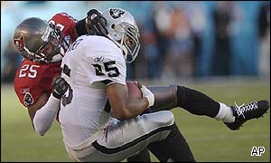 Tampa Bay Buccaneers cornerback Brian Kelly, left, tackles Oakland Raiders running back Charlie Garner 
