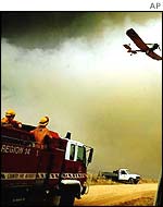 A firefighter plane flies as firefighters battle bush fires heading for the town of Omeo in the Alpine region in Victoria state