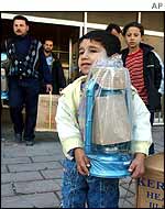 Iraqi child holds lantern as his family shops for emergency provisions