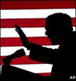 George W Bush in silhouette standing in front of the US flag 