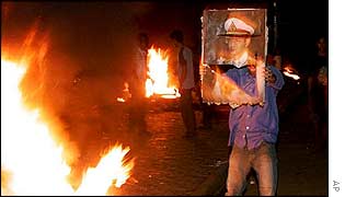 Cambodian youth prepares to throw a portrait of Thailand's King Bhumibol Adulyadej on a fire during the burning and looting of the Thai embassy in Phnom Penh, 29 Jan 2003.