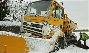A tow-truck driver digs a grit spreader out of the snow in Cambridge 