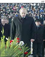 Russian President Vladimir Putin observes a moment of silence as he lays a wreath