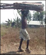 A displaced boy carries material to build a hut in the camp