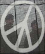 British troops stand guard behind a CND slogan displayed on a banner 