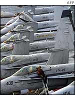 A US navy plane captain sits on the wing of an F/A-18 Hornet aboard the USS Abraham Lincoln,