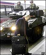 A passenger walks in front of troops at Heathrow