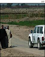A UN inspectors' vehicle passes Iraqis