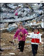 Children walk in front of demolished houses in Beit Lahiya