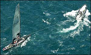 The damaged New Zealand boat, NZL-82, is towed back to port after retiring from the race