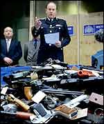 Sir John Stevens shows weapons collected during a guns amnesty