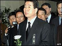 South Korean President-elect Roh Moo-Hyun (C) stands with a carnation in front of an altar