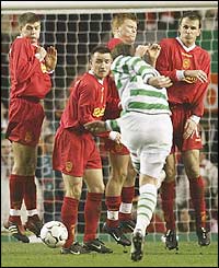 The Liverpool wall leap into the air but Celtic midfielder Alan Thompson blasts the ball underneath them