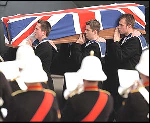 Royal Navy personnel carry the flag-draped coffin at RAF Brize Norton