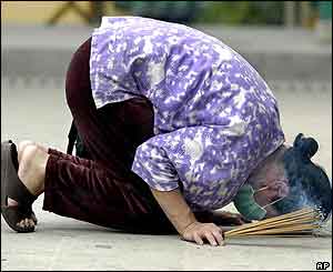 A woman wearing mask in an attempt to protect herself from SARS, prays with incenses in a Hong Kong Temple 