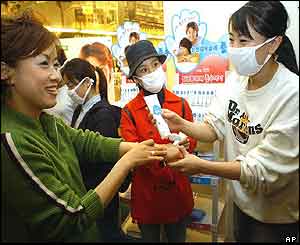 An employee of South Koreas Paru Company, right, gives a hand sanitising cream to the customers