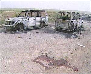 A pool of blood surrounds two blown-up vehicles 