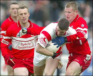 Colin Holmes of Tyrone is held up by Niall McCusker