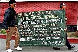 Teachers carry a blackboard reading Undefined national strike: No more abuses and promises!