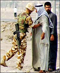 A British soldier checks two men at the entrance to Basra 
