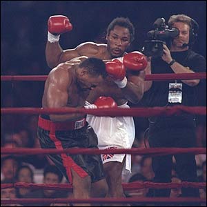 Oliver McCall stumbles as Lennox Lewis looks on during a bout at the Las Vegas Hilton in Las Vegas, Nevada. Lewis won the fight