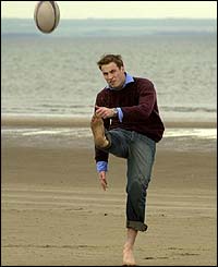 William kicks a rugby ball on the beach