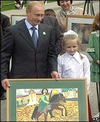 Russian President Vladimir Putin holds a picture by eight-year-old Alexandra Abramova