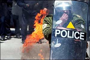 Policeman with burning petrol bomb behind him