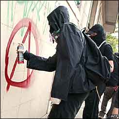 Anarchy symbol being spray-painted on a wall
