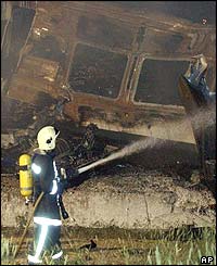 Burnt-out passenger train carriages being doused 