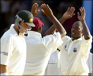 West Indies' Vasbert Drakes (right) celebrates taking the wicket of Justin Langer in the sixth over