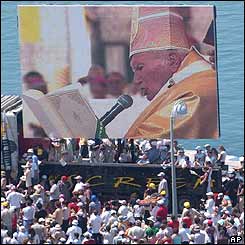 People watch Pope John Paul II on a video screen during the mass 
