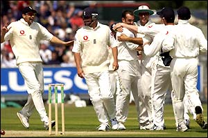The England team crowd round to celebrate Richard Johnson's dismissal of Stuart Carlisle