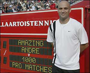 Agassi poses next to the Queen's club scoreboard that highlights his 1,000th match