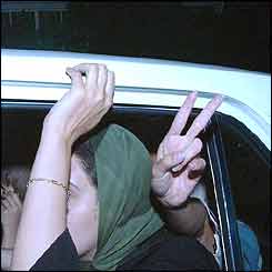 Woman flashes a v-sign from a car, while another hides her face