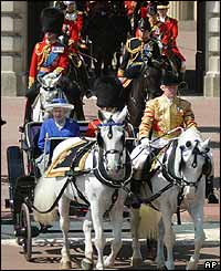 The Queen rides in an open carriage pulled by two greys 