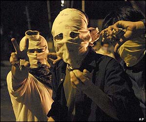 Students in masks flash the peace sign