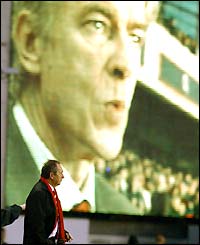 Gerard Houllier is overshadowed by the image of Arsene Wenger on the big screen