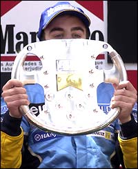 Home favourite Alonso shows his fans the trophy 