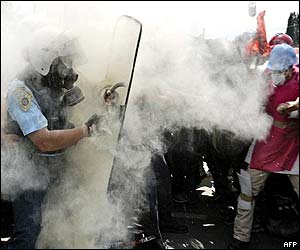 Fighting riot police and protesters are engulfed in tear gas 