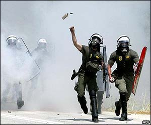 Police officer throws tear gas canister at protesters 