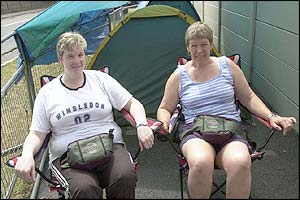Two tennis fans queue outside the front of the All England Club