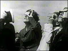 People peering through squares of glass at the sun