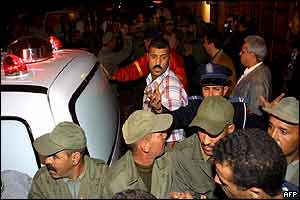 Policemen try to stop people from approaching the Casa de Espana restaurant as an ambulance leaves the place 