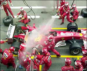 Mechanics race to put out a fire on Schumacher's car during his first pit