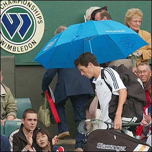 Tim Henman heads off court under an umbrella
