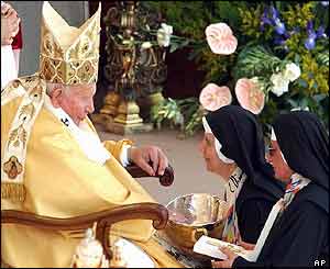 Two nuns present Pope John Paul II with a bowl and crucifix during a solemn Mass to proclaim four new saints