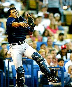 Miguel Ojeda of the San Diego Padres tries to throw out a runner at first base after a wild pitch against the LA Dodgers