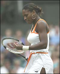 Serena Williams looks thoughtful as she plays with her racket strings